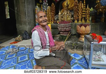 "Elderly Cambodian woman, novice with incense sticks, in front of a Buddha statue, Angkor Wat temple complex, Siem Reap, Cambodia, Asia" View Large Photo Image Stock Photo - "Elderly Cambodian woman, novice with incense sticks, in front of a Buddha statue, Angkor Wat temple complex, Siem Reap, Cambodia, Asia". Fotosearch