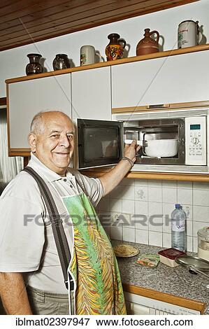 Elderly man cooking with a microwave oven View Large Photo Image Stock Photo - Elderly man cooking with a microwave oven. Fotosearch