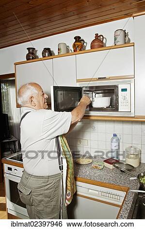 Elderly man cooking with a microwave oven View Large Photo Image Stock Photograph - Elderly man cooking with a microwave oven. Fotosearch