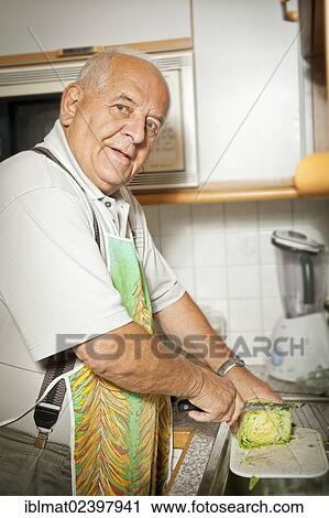 Elderly man cutting salad in a kitchen View Large Photo Image Stock Image - Elderly man cutting salad in a kitchen. Fotosearch