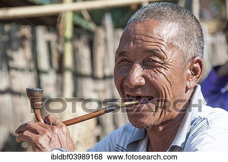 Stock Photo - "Elderly man from the Akha people, hill tribe, ethnic minority, smoking a pipe, portrait, Chiang Rai Province, Northern Thailand, Thailand, Asia". Fotosearch