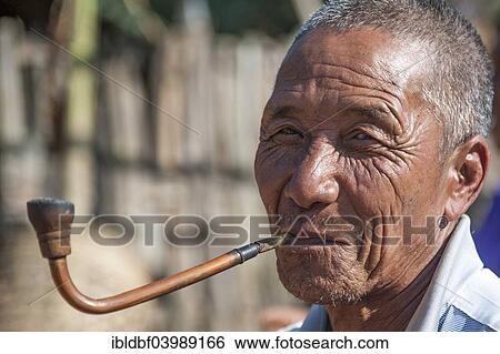 Stock Photograph - "Elderly man from the Akha people, hill tribe, ethnic minority, smoking a pipe, portrait, Chiang Rai Province, Northern Thailand, Thailand, Asia". Fotosearch