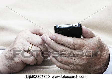 Elderly man holding a smartphone in his hand View Large Photo Image Stock Image - Elderly man holding a smartphone in his hand. Fotosearch
