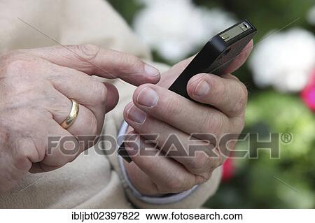 Elderly man holding a smartphone in his hand View Large Photo Image Stock Image - Elderly man holding a smartphone in his hand. Fotosearch