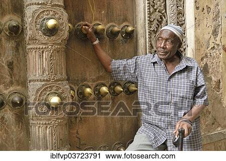 "Elderly man leaning against a wooden door in the historic town centre, Zanzibar City, Zanzibar, Tanzania, Africa" View Large Photo Image Stock Image - "Elderly man leaning against a wooden door in the historic town centre, Zanzibar City, Zanzibar, Tanzania, Africa". Fotosearch