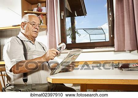 Elderly man reading a newspaper with a magnifying glass View Large Photo Image Stock Image - Elderly man reading a newspaper with a magnifying glass. Fotosearch