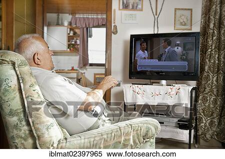 Elderly man sitting in front of a TV operating a remote control View Large Photo Image Stock Photography - Elderly man sitting in front of a TV operating a remote control. Fotosearch