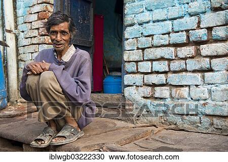 Stock Image - "Elderly man sitting on a step in front of his house, Agra, Uttar Pradesh, India, Asia". Fotosearch