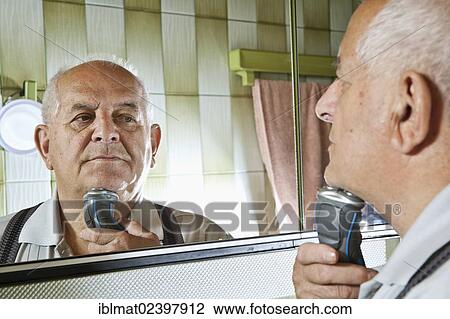 Stock Image - Elderly man using an electric shaver. Fotosearch
