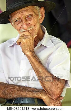 "Elderly man with a hat, holding hand to his chin, Poxoreo, Mato Grosso, Brazil, South America" View Large Photo Image Stock Photo - "Elderly man with a hat, holding hand to his chin, Poxoreo, Mato Grosso, Brazil, South America". Fotosearch