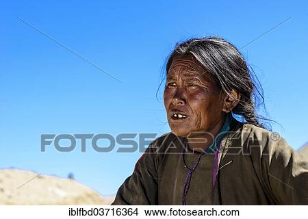 Picture - "Elderly nomad woman, snow covered mountains in the distance, Korzok, Ladakh, Jammu and Kashmir, India, Asia". Fotosearch