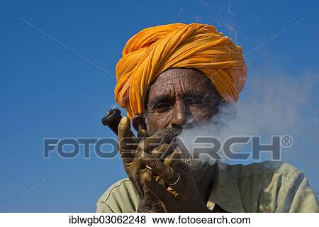 "Elderly Rajasthani man with an orange turban smoking a hash pipe or hooka, Kamelmarkt,, Pushkar, Rajasthan, India, Asia" View Large Photo Image Stock Photo - "Elderly Rajasthani man with an orange turban smoking a hash pipe or hooka, Kamelmarkt,, Pushkar, Rajasthan, India, Asia". Fotosearch