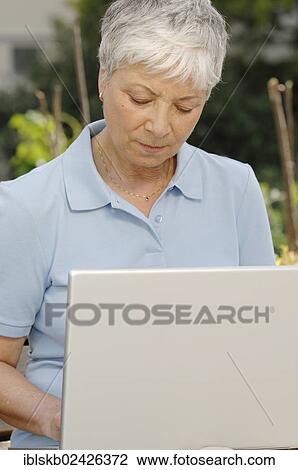 "Elderly woman, gray-haired, 55-65, working outdoors on a laptop" View Large Photo Image Stock Image - "Elderly woman, gray-haired, 55-65, working outdoors on a laptop". Fotosearch