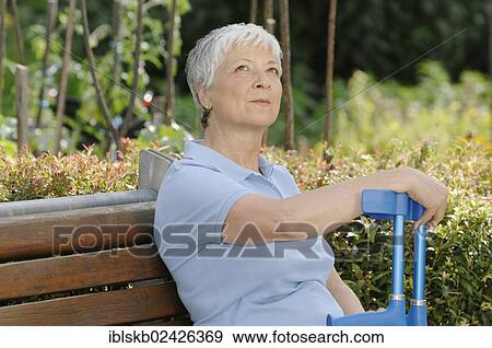 "Elderly woman, gray-haired, 55-65, sitting on a park bench with a pair of crutches in her hand" View Large Photo Image Stock Photo - "Elderly woman, gray-haired, 55-65, sitting on a park bench with a pair of crutches in her hand". Fotosearch