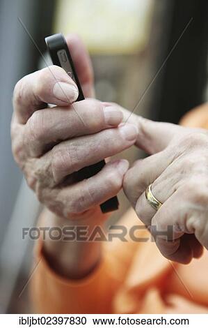 Elderly woman holding a smartphone in her hand View Large Photo Image Stock Image - Elderly woman holding a smartphone in her hand. Fotosearch