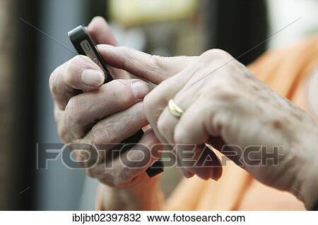 Elderly woman holding a smartphone in her hand View Large Photo Image Stock Image - Elderly woman holding a smartphone in her hand. Fotosearch