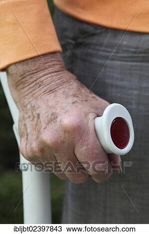 Stock Image - Elderly woman standing with a crutch in her hand. Fotosearch
