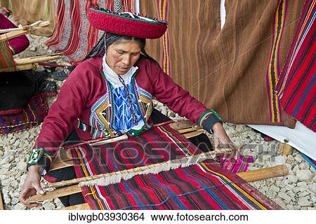 Picture - "Elderly woman wearing a hat, Quechua Indian in traditional dress working on a loom, Cinchero, Urubamba Valley, Peru, South America". Fotosearch