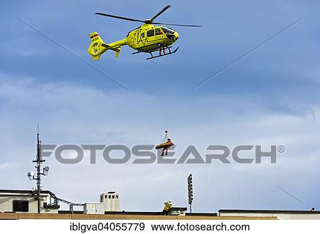 Stock Photo - "Eurocopter EC135 T2 + rescue helicopter of the Geneva University Hospital, Hopitaux Universitaire de Geneve, HUG, hovering above the roof of a house during an emergency flight, Canton of Geneva, Switzerland, Europe". Fotosearch