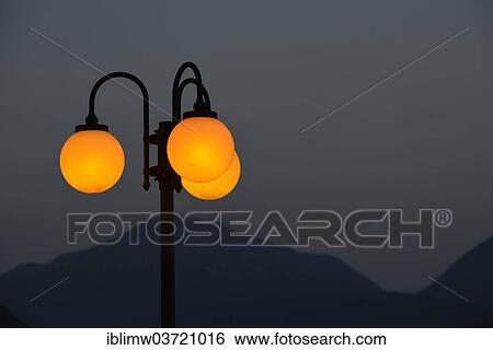 "Evening mood, illuminated street lamp in front of Monte San Giorgio, Porto Ceresio, Lombardy, Italy, Europe" View Large Photo Image Stock Photograph - "Evening mood, illuminated street lamp in front of Monte San Giorgio, Porto Ceresio, Lombardy, Italy, Europe". Fotosearch