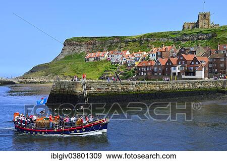 "Excursion boat entering the harbour, St. Mary's Church at back, Whitby, North Yorkshire, England, United Kingdom, Europe" View Large Photo Image Stock Photo - "Excursion boat entering the harbour, St. Mary's Church at back, Whitby, North Yorkshire, England, United Kingdom, Europe". Fotosearch