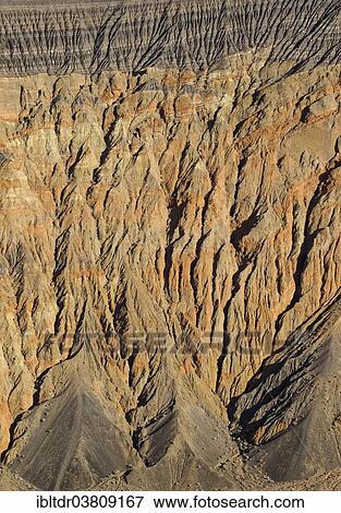 Stock Photo - "Exposed fissured bedrock of orange-colored conglomerate on the crater wall of Ubehebe Crater, Death Valley, Death Valley National Park, California, USA". Fotosearch