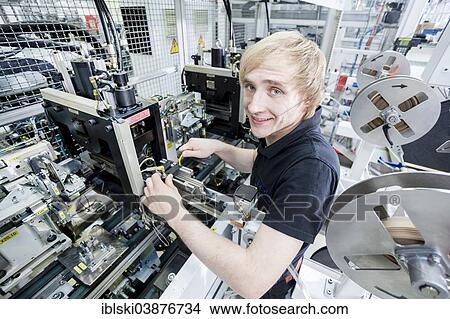 Picture - "Fabian Kerscher, best trainee nationwide in 2013 in the field of mechatronics, adjusting the sensor position at a punch, Technical Plastic Systems GmbH company, Wackersdorf, Bavaria, Germany, Europe". Fotosearch