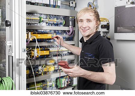 Stock Image - "Fabian Kerscher, best trainee nationwide in 2013 in the field of mechatronics, voltage measurement in a control cabinet, Technical Plastic Systems GmbH company, Wackersdorf, Bavaria, Germany, Europe". Fotosearch