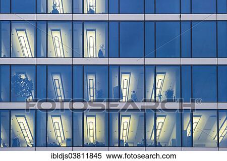 Stock Photography - "Facade of a modern office building with lights on in the offices in the evening, Munich, Bavaria, Germany, Europe". Fotosearch