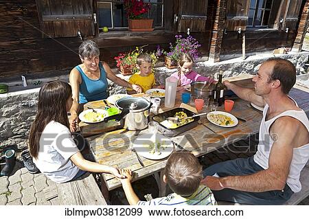 "Family holding hands before lunching together in front of a mountain chalet, Alp Gun, Graubunden, Switzerland, Europe" View Large Photo Image Stock Photo - "Family holding hands before lunching together in front of a mountain chalet, Alp Gun, Graubunden, Switzerland, Europe". Fotosearch