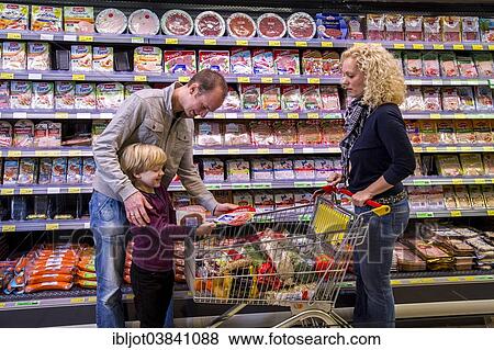 "Family shopping with a shopping trolley in the packed meat department of a supermarket, Germany, Europe" View Large Photo Image Stock Photo - "Family shopping with a shopping trolley in the packed meat department of a supermarket, Germany, Europe". Fotosearch