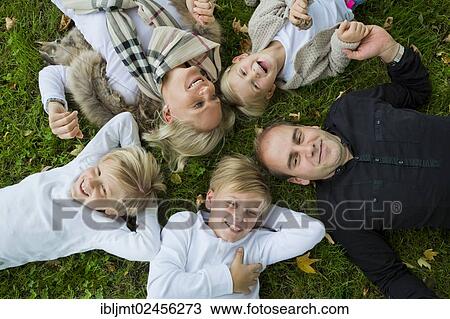 Family with three children lying on the grass View Large Photo Image Stock Image - Family with three children lying on the grass. Fotosearch