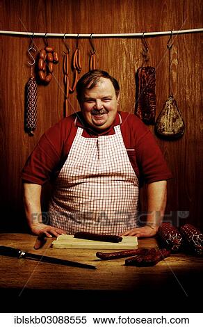 Fat butcher smiling with his hands propped on a bench in a butcher's store with a wooden ambience View Large Photo Image Stock Photography - Fat butcher smiling with his hands propped on a bench in a butcher's store with a wooden ambience. Fotosearch