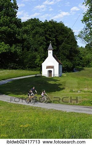 Stock Image - Father and children cycling, mountain biking, Chapel of St. Ulrich, Muehltal valley, Pupplinger Au, near Wolfratshausen, Upper Bavaria, Bavaria, Germany, Europe. Fotosearch