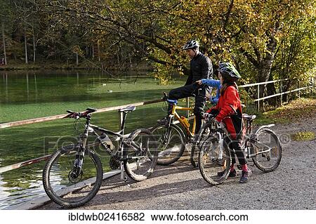Stock Image - Father and children riding mountain bikes, at Badersee lake in Grainau, Werdenfelser Land, Upper Bavaria, Bavaria, Germany, Europe. Fotosearch