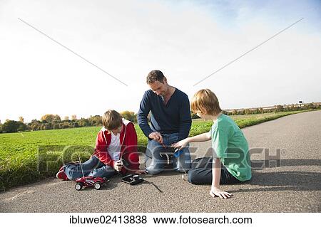 Father tinkering on a remote-controlled model car with his sons View Large Photo Image Stock Photo - Father tinkering on a remote-controlled model car with his sons. Fotosearch