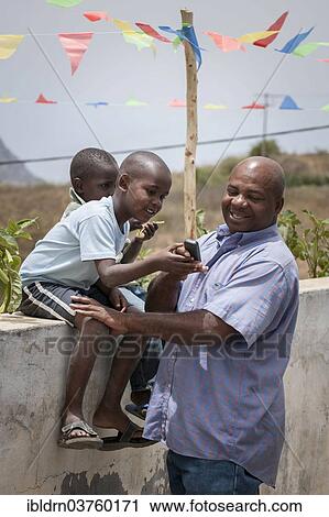 Stock Image - "Father with two children, Rui Vaz, Santiago, Cape Verde, Africa". Fotosearch