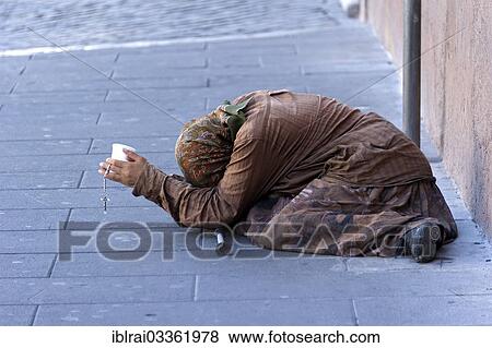 Stock Photo - "Female beggar holding a plastic cup in a street of the old town, Rome, Lazio, Italy, Europe". Fotosearch