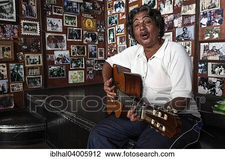 Stock Image - "Female Cuban musician playing the guitar in a Casa de la Trova, Santiago de Cuba, Cuba, North America". Fotosearch