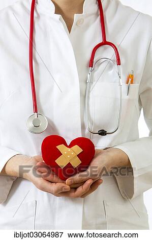 "Female doctor holding a red heart with a plaster in her hands, symbolic image for a heart attack" View Large Photo Image Stock Photo - "Female doctor holding a red heart with a plaster in her hands, symbolic image for a heart attack". Fotosearch
