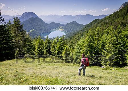Stock Image - "Female hiker observing the view from the Wilder-Kaiser-Steig hiking trail towards Lake Hintersteiner See, in the Wilder Kaiser Mountains, Kaisergebirge, near Ellmau, Tyrol, Austria, Europe". Fotosearch