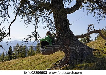 Stock Image - "Female hiker sitting on a cut off branch, Buergeralm alp, Aflenz, Bruck an der Mur, Styria, Austria, Europe". Fotosearch