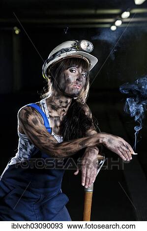 Stock Image - "Female mine worker holding a cigarette, Innsbruck, Tyrol, Austria, Europe". Fotosearch