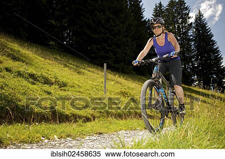 Stock Photography - "Female mountain biker riding a bike in the Alps near Lauenen, Canton Bern, Switzerland, Europe". Fotosearch