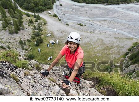 Stock Image - "Female mountain climber climbing a fixed rope climbing route, Vallee de la Romanche valley, Villar-d'Arene, Provence-Alpes-Cote d'Azur, France, Europe". Fotosearch