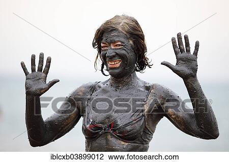 Stock Image - "Female tourist covered in salty mud from the Dead Sea, Suwayma, Jordan, Asia". Fotosearch