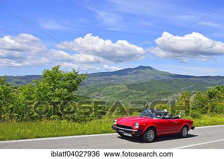 "Fiat 124 Spider convertible, classic car, on road through hilly landscape, near Radicofani, Tuscany, Italy, Europe" View Large Photo Image Stock Photograph - "Fiat 124 Spider convertible, classic car, on road through hilly landscape, near Radicofani, Tuscany, Italy, Europe". Fotosearch
