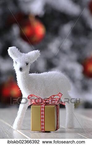 Figure of a white fawn with a golden gift in a Christmas ambience View Large Photo Image Stock Image - Figure of a white fawn with a golden gift in a Christmas ambience. Fotosearch