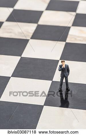 "Figurine of a businessman standing on a chessboard, pensive" View Large Photo Image Stock Photo - "Figurine of a businessman standing on a chessboard, pensive". Fotosearch