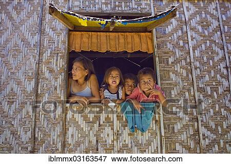 Stock Photo - "Filipino mother and children looking out of a window of their home, Malapascua Island, Philippines, Asia". Fotosearch